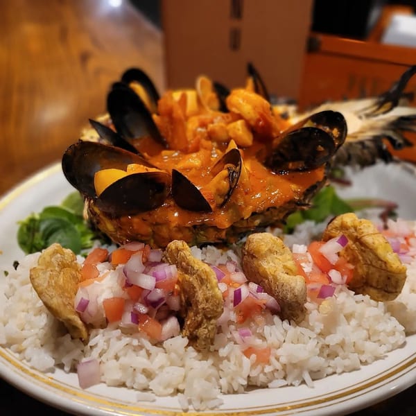 Cuban seafood dish with mussels, shrimp, and rice topped with diced tomatoes and red onions.